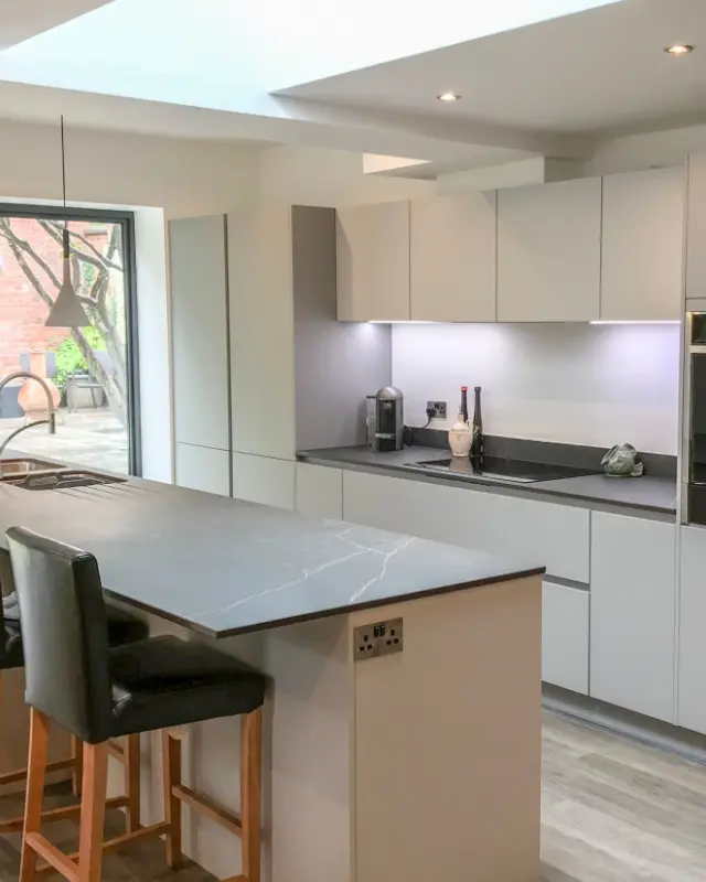 Moderne grifflose Küche mit Kücheninsel und Natursteinarbeitsplatte in einer Frankfurter Wohnung